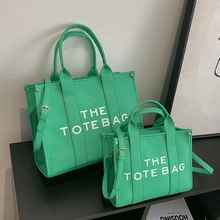 Detail of bright green canvas tote bags in two sizes with the tote bag print and straps