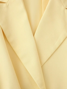 Gros plan du revers d'un blazer jaune pâle montrant la texture du tissu sergé