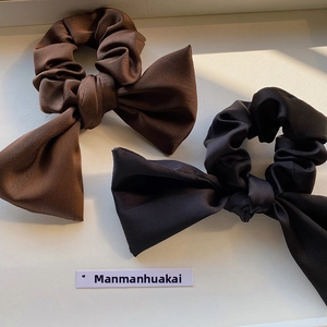Detailed macro view of elegant satin bow scrunchies in coffee and black silk fabric