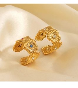Macro detail of gold floral ring with colorful zircon inlays on champagne silk fabric