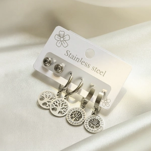 Silver stainless steel tree of life earring set on white card over silk background