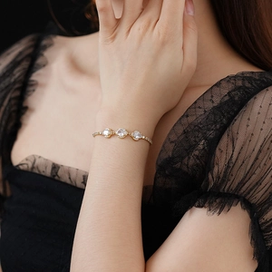 Close-up of gold adjustable flower bracelet with oval zircons on a model wrist