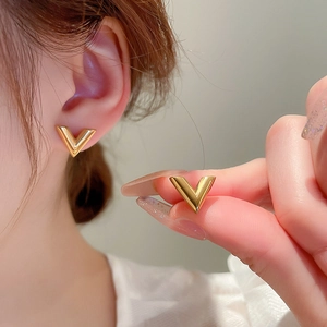 Élégantes boucles d'oreilles en V dorées en acier inoxydable portées par le mannequin