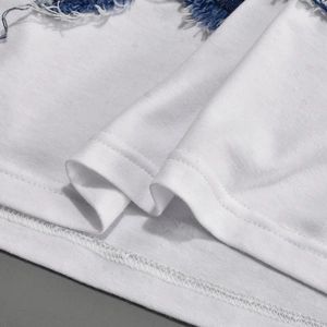 Detail of white knit fabric with blue denim frayed edge and double needle hem stitching