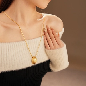 Gros plan d'un collier pendentif ovale doré avec une chaîne serpent sur un mannequin