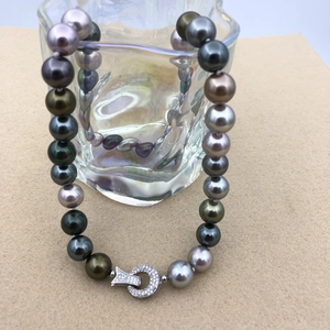 Detail of multi-color Tahitian style pearl necklace draped on textured glass