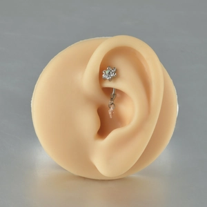 Detail of G23 titanium belly ring with flower zircon and opal drop on a model ear