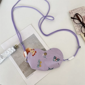 Détail du sac violet en forme de cœur avec broderie papillon et bouton pression en métal