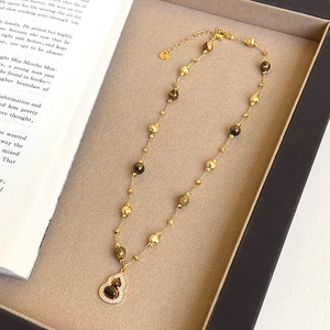Detail of 18K gold-plated necklace featuring tiger eye gourd pendant and brown beads
