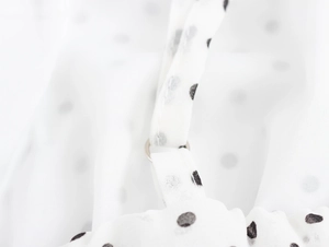 Détail de la bretelle réglable et de l'anneau sur la robe blanche à pois