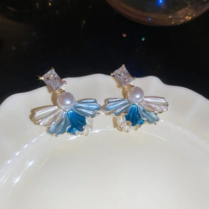 Macro detail of blue enamel flower earring with pearl and square crystal on porcelain