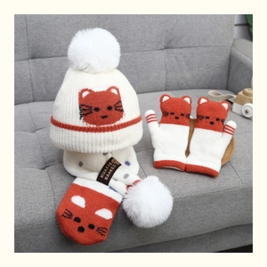 Detailed close-up of winter knitted set with cat pattern beanie, scarf, and mittens