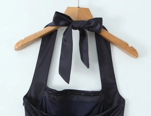 Détail d'une robe dos nu en satin noir avec un grand nœud élégant à l'arrière du col