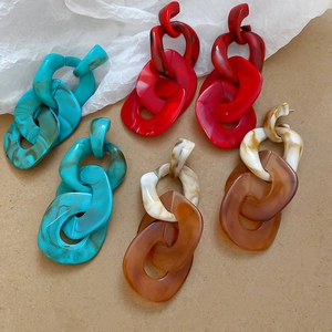 Detail view of large acrylic chain link earrings in marble blue red and amber finishes