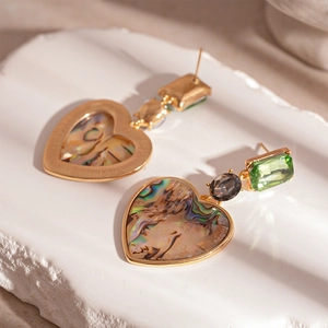 Dettaglio macro di orecchini vintage a cuore con gemma verde e intarsio in conchiglia