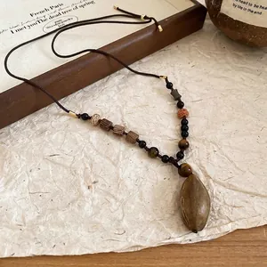Vintage ethnic necklace with natural brown stone pendant and wooden beads on textured paper