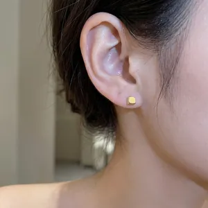 Minimalist geometric cube stud earrings in gold finish worn for a daily commute style