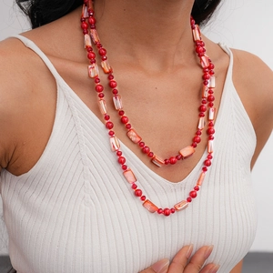 Close-up of layered necklace with red crystal beads and irregular shell pendants