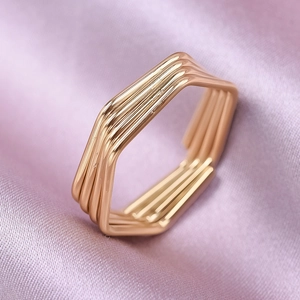 Detail view of rose gold multi-layer hexagonal ring on pink satin fabric background