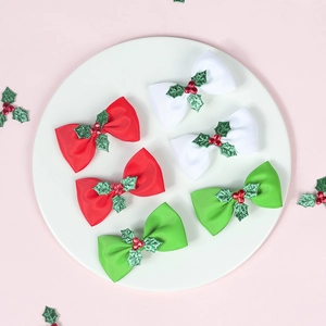 Top view of red, white, and green Christmas ribbon hair bows with glittery holly leaves