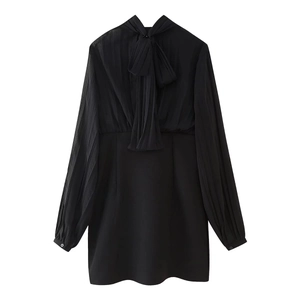Detail of black chiffon dress featuring an elegant bow tie neck and pleated texture