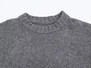 Gros plan du col rond côtelé sur un pull en maille texturée gris anthracite foncé