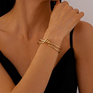 Close-up of minimalist double-layered knotted gold bracelet worn on a female wrist