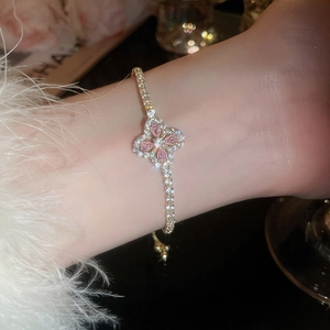 Détail du bracelet trèfle rose avec cristaux étincelants porté sur le poignet délicat