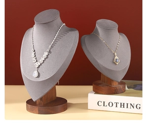 Close-up of gold and silver necklaces displayed on a gray fabric jewelry bust stand