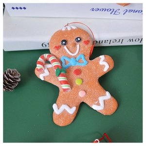Close-up of gingerbread man ornament with candy cane and red string on green background