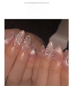Detail of short almond press-on nails with nude cat-eye glitter, butterfly and pearls