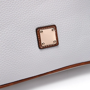 Close-up of white lychee grain leather handbag with gold metal plaque and brown piping detail