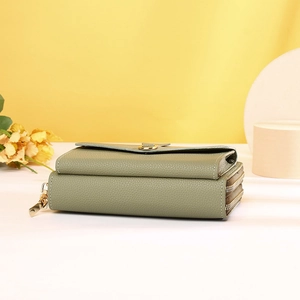 Detail of sage green lychee textured crossbody bag showing triple zipper layers and gold buckle
