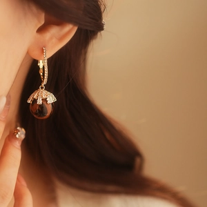Close-up of leopard print sphere earrings with gold zircon details worn by a model