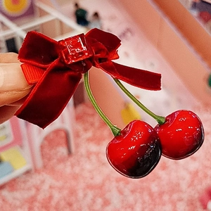 Détail d'une barrette en velours rouge avec des cerises et une boucle carrée élégante