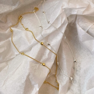 Close-up of minimalist gold and silver heart-shaped pendants on fine chain necklaces