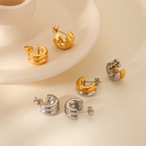 Close-up of three pairs of C-shaped 18K gold and silver chunky double-layered earrings