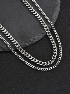 Detailed close-up of double-layered silver twist chain necklace on dark stone surface