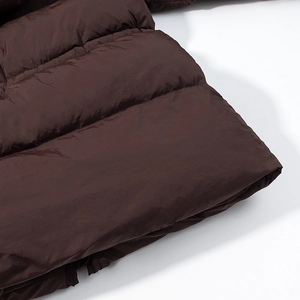 Detailed view of horizontal quilting on dark brown mid-length padded winter coat fabric