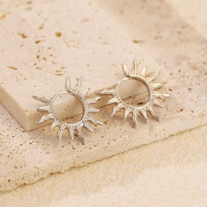 Detail of silver S925 sunburst hoop earrings displayed on aesthetic stone props