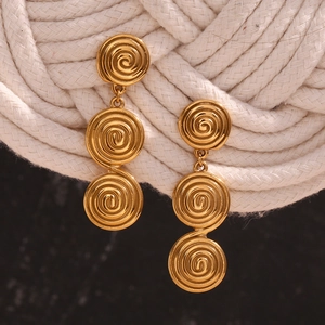 Vue rapprochée de boucles d'oreilles spirales en acier doré sur une corde de coton