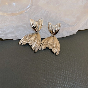 Macro detail of silver fishtail stud earrings with elegant curved lines and metallic polish