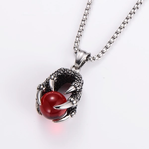 Detail of silver eagle claw pendant holding a red bead with vintage metal box chain
