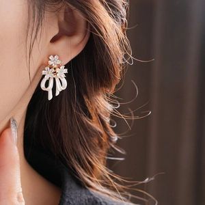 Détail de boucles d'oreilles élégantes plaquées or avec fleurs et nœuds sur le mannequin
