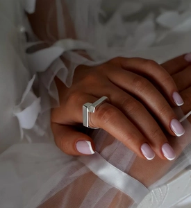 Close-up of a minimalist S925 sterling silver geometric cross ring worn on the index finger