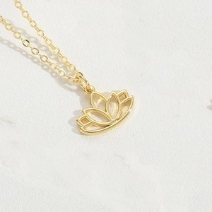 Macro shot of gold lotus flower pendant necklace on white textured leather surface