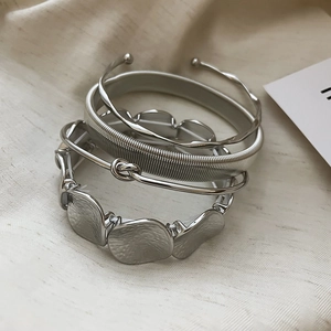 Detail of four-piece silver metal bracelet set with twisted and textured patterns