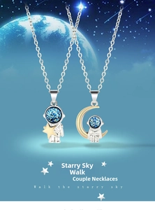 Detail of silver astronaut pendants with blue glitter helmets on starry sky background