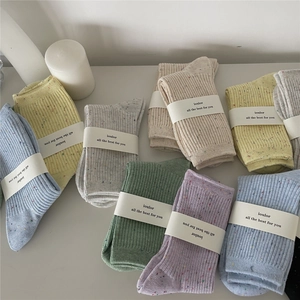Flat lay of colorful dot-patterned cotton crew socks with minimalist packaging labels