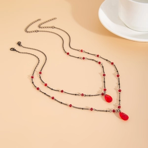 Macro detail of gothic choker featuring red faceted beads and teardrop blood charms